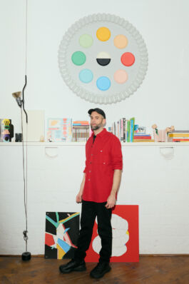 Mariano Pascual in rotem Hemd im Studio vor rundem Farbpaletten-Kunstwerk an der Wand David Baglietto Fotograf Hamburg